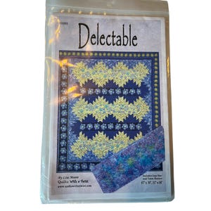 May include: A quilt pattern titled "Delectable" in a plastic sleeve. The pattern features a blue and yellow starburst design. Includes lap size and table runner dimensions: 67" x 76" and 21" x 56". The pattern is by Lisa Moore, "Quilts With a Twist".
