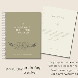 May include: A spiral-bound journal titled "The Menopause Brain Fog Tracker" in olive green, with floral illustrations. The open page reads "Welcome" with text. Additional text includes "Daily Support for Mental Clutter" and "Feel more organized & Less Overwhelmed."