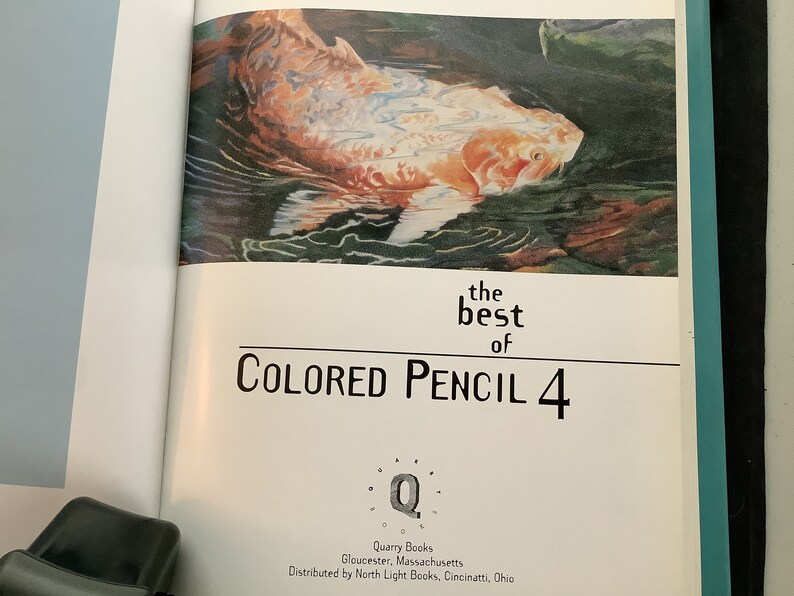 K&ouml;nnte beinhalten: Das Cover des Buches The Best of Colored Pencil 4 zeigt ein farbenfrohes Gem&auml;lde eines Fisches, der im Wasser schwimmt. Das Buch wird von Quarry Books herausgegeben und von North Light Books vertrieben.