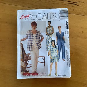 May include: A vintage sewing pattern from Easy McCall's, featuring a woman in a plaid shirt and pants, and other clothing styles. The pattern is labeled "Womanstyle" and "Petite-Able".
