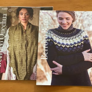 May include: Two magazines with women wearing knitted garments. The magazine on the left is titled "Berroco Quechua" and features a woman wearing a green shawl. The magazine on the right is titled "Berroco Bento" and features a woman wearing a patterned sweater.