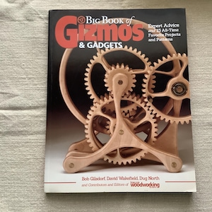 May include: The cover of "Big Book of Gizmos & Gadgets" features a wooden gear mechanism. The title is in red and the book includes expert advice and 15 favorite projects. The book is by Bob Gilsdorf, David Wakefield, and Dug North.