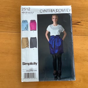May include: A Simplicity sewing pattern featuring a Cynthia Rowley design. The pattern includes illustrations of various skirt styles. The cover shows a woman wearing a white top and a blue skirt. The pattern number is 2512.