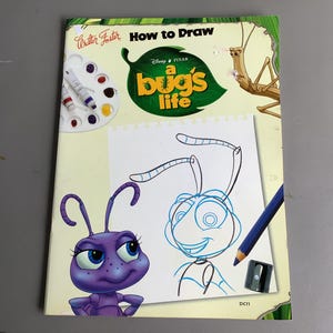 May include: A "How to Draw" book featuring Disney Pixar's "A Bug's Life." The cover displays a drawing of an ant, a pencil, a sharpener, and a watercolor palette. The book has the title "A Bug's Life" in green and yellow.