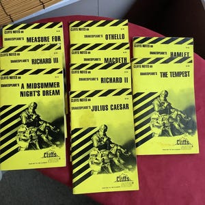 May include: A collection of vintage Cliffs Notes study guides for Shakespeare's plays. The books have yellow covers with black diagonal stripes and illustrations. Titles include "Measure for Measure," "Othello," and "Hamlet."