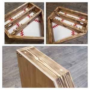 Puede incluir: Un estante de madera con forma de béisbol con tres niveles. El estante está teñido de marrón oscuro y tiene un fondo blanco con costuras rojas. El estante está diseñado para sostener bates de béisbol u otros equipos deportivos.