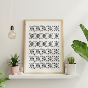 May include: Black and white framed print with a repeating pattern of stylized flowers and leaves. The print is hanging on a white wall.