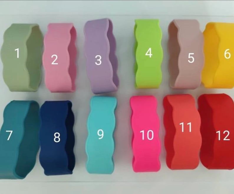 May include: A collection of twelve silicone wristbands featuring a wavy, scalloped edge design. Each band is a solid color, numbered one through twelve, including shades of sage green, pink, lavender, lime green, beige, yellow, teal, navy, cyan, hot pink, coral, and red.