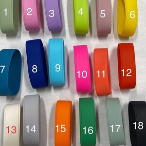 May include: A collection of eighteen silicone wristbands in various solid colors, each labeled with a white number from 1 to 18. The colors include shades of green, pink, purple, yellow, blue, orange, red, white, gray, and black in a matte finish.