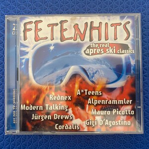 Puede incluir: Una caja de CD para "Fetenhits", con el texto "the real après ski classics". La portada presenta gafas de esquí sobre un fondo de fuego. Los artistas incluyen Rednex, Modern Talking y Gigi D'Agostino.