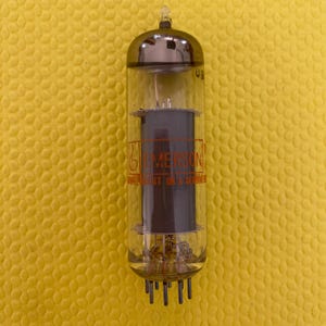 Puede incluir: Tubo de vac&iacute;o vintage con una carcasa de vidrio transparente y una parte superior plateada. El tubo tiene componentes internos y una estructura cil&iacute;ndrica de color gris oscuro. El texto "EMERSON" es visible. El tubo tiene m&uacute;ltiples pines en la base.
