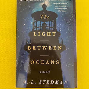 May include: A novel by M.L. Stedman, "The Light Between Oceans", with a lighthouse silhouette on the cover against a starry night. The book is a New York Times Bestseller. Includes a quote from USA Today.