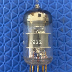 May include: A clear glass valve with a rounded top and gold pins. The valve has internal components and the number "6922" printed on the side. The valve is designed for electronic devices.