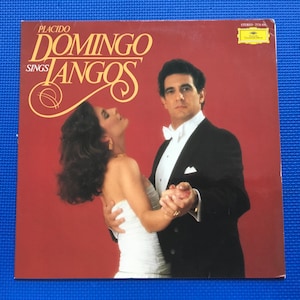 May include: A red vinyl record album cover featuring a man and woman dancing. The album title is "Placido Domingo Sings Tangos".