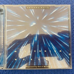 Peut inclure: Un boîtier de CD en plastique transparent contenant deux disques compacts. La couverture présente un design bleu et blanc avec les mots "Millennium Worship" et "Experiencing God In Worship". Le texte "Hosanna Music" est également visible.