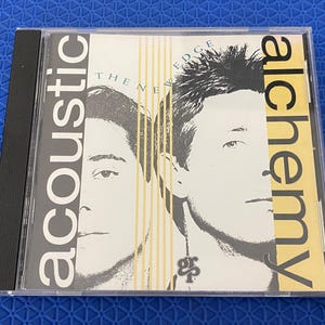 Könnte beinhalten: Acoustic Alchemy CD-Album in einer transparenten Jewel-Case. Das Albumcover zeigt zwei Graustufenporträts von Männern, mit dem Bandnamen und Albumtitel in fetter Schrift. Der Hintergrund hat vertikale gelbe Streifen.