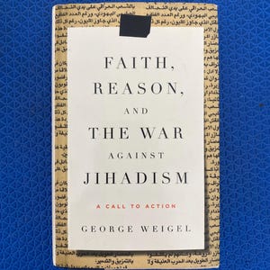 May include: A book titled "FAITH, REASON, AND THE WAR AGAINST JIHADISM" by George Weigel. The book cover is white with black text and a red subtitle, set against a background of newspaper print and a blue surface.