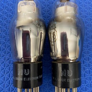 May include: Two vintage vacuum tubes with clear glass bulbs and black bases. The bases are labeled "NU" and "NATIONAL UNION ELECTRON TUBE". The tubes have multiple pins and metallic internal components.