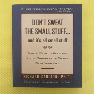 May include: A hardcover book titled "DON'T SWEAT THE SMALL STUFF..." with the subtitle "and it's all small stuff." The book is dark blue with white and brown text. The author's name, Richard Carlson, Ph.D., is also displayed.