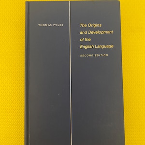 May include: A dark blue hardcover book titled "The Origins and Development of the English Language, Second Edition" by Thomas Pyles. The book has gold lettering and a white vertical line. The background is yellow.