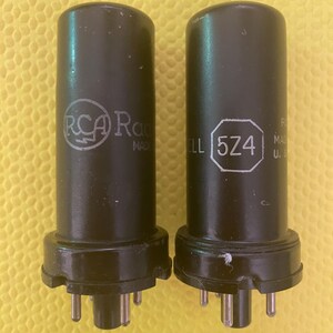 May include: Two black vacuum tubes with silver pins. The tube on the left has the text "RCA Radiotron Made in USA" printed on it. The tube on the right has the text "5Z4" printed on it.