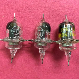 May include: Three vintage vacuum tubes with clear glass bulbs and metal components, connected by a wire. Each tube has the RCA logo and the number "95" printed on them. The third tube has the text "THOMAS MADE IN USA".