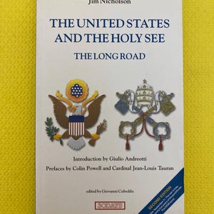 Pode incluir: Um livro intitulado "THE UNITED STATES AND THE HOLY SEE THE LONG ROAD" de Jim Nicholson. A capa apresenta o selo dos EUA e símbolos papais. É uma segunda edição, editada por Giovanni Cubeddu, com introduções e prefácios.