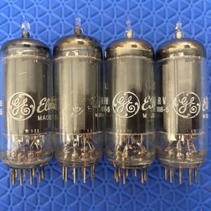 May include: Four vintage GE vacuum tubes with glass enclosures and metal pins. Each tube has a silver top and a clear glass body, with the GE logo and "RV 188-5" printed on the side. The tubes are arranged against a blue background.