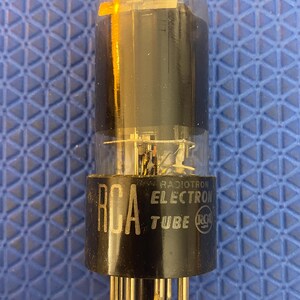 Puede incluir: Un tubo de electrones RCA Radiotron vintage. El tubo tiene una carcasa de vidrio transparente con una base negra y una serie de pines. El logotipo de RCA y las palabras "RADIOTRON ELECTRON TUBE" están impresas en la base.
