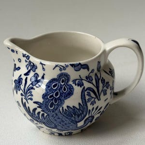 May include: A white ceramic mug with a black handle and the text "But First, Coffee" in a black, handwritten-style font. The mug is likely 11-15 ounces in size, perfect for a morning beverage.