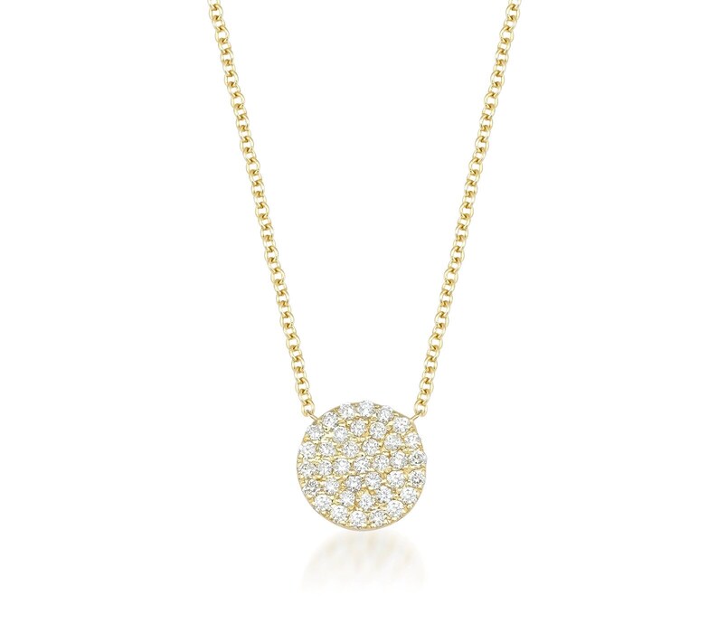 May include: A gold necklace with a circular pendant set with numerous small diamonds. The pendant hangs from a fine gold chain, creating a simple and elegant design. The necklace is displayed against a white background.