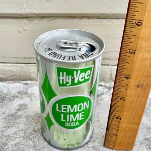 May include: A silver aluminium can of Hy-Vee Lemon Lime Soda. The can has a green and white label with the text "Hy-Vee Lemon Lime Soda" and "12 fluid ozs".