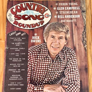 May include: A vintage Country Song Roundup magazine cover featuring Buck Owens. The cover features a photo of Buck Owens, a red and white checkered shirt, and the text "Country Song Roundup" in a large, bold font.