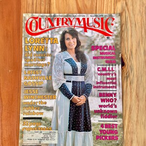 May include: A magazine cover featuring country music singer Loretta Lynn. The cover is titled "Country Music" and features a photo of Lynn in a white and blue dress. The text on the cover includes the headline "Loretta Lynn: Did success spoil her marriage?" and other articles about country music.