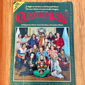 May include: A vintage Country Music magazine cover featuring a group of country music stars gathered around a Christmas wreath. The cover features the text "A Night on the Town with Tompall Glaser", "The Joy is Back in Connie Smith's Singing", "Country Music", and "A Christmas Cheer from the Stars of Country Music".