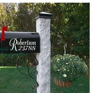 May include: Black mailbox with a white vinyl decal that says "Robertson 23788". The mailbox is mounted on a gray stone post with a black metal mailbox holder.