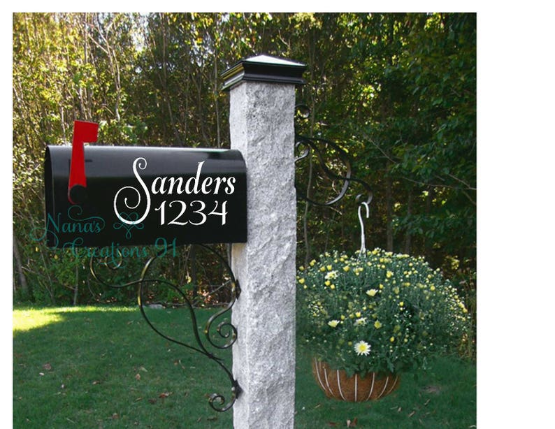 May include: Black mailbox with a white vinyl decal that says "Sanders 1234" with a decorative swirl. The mailbox is mounted on a gray stone post.