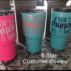 May include: Three stainless steel tumblers with a white design that reads "There's a chance this is ..."  The tumblers are pink, turquoise, and turquoise. The pink tumbler says "...vodka", the first turquoise tumbler says "...whiskey", and the second turquoise tumbler says "...beer".