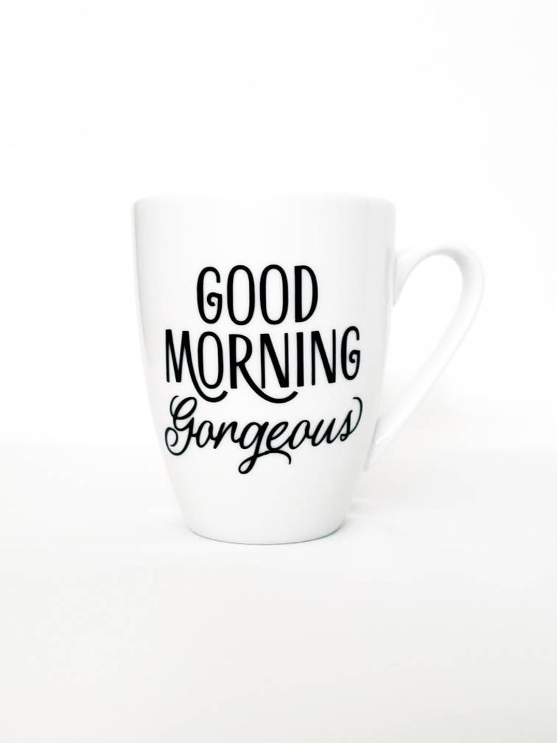 May include: White ceramic coffee mug with black text that reads "Good Morning Gorgeous".