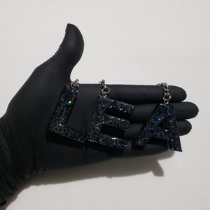 Llavero plateado con brillantina de galaxia y letras negras