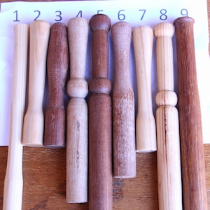 Peut inclure: Neuf maillets en bois, numérotés de 1 à 9, avec des tons et des finitions de bois variés. Les maillets sont disposés en rangée sur une surface en bois.