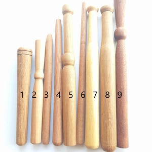 Peut inclure: Neuf chevilles en bois de différentes longueurs et diamètres, numérotées de 1 à 9. Les chevilles sont disposées horizontalement sur un fond blanc.