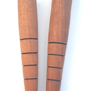 May include: Two wooden plant stakes with a tapered design and multiple rings. The stakes are brown and have a natural wood finish.