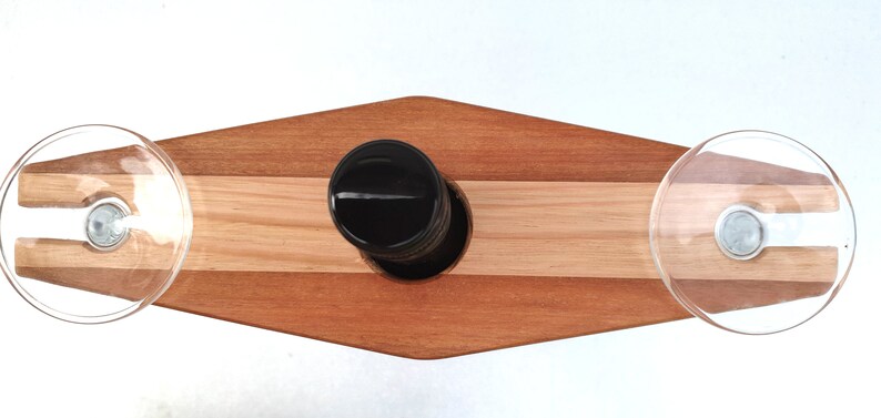 May include: A wooden wine rack with two suction cups for holding wine glasses. The rack is made of light and dark wood and has a diamond shape.
