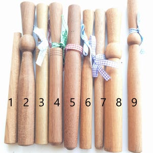 Peut inclure: Neuf chevilles en bois de différentes longueurs et diamètres, attachées avec des rubans colorés. Les chevilles sont numérotées de 1 à 9.