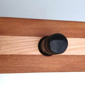 May include: A wooden serving tray with two glass holders and a center slot for a bottle. The tray is made of two types of wood, one light and one dark, and has a natural finish.