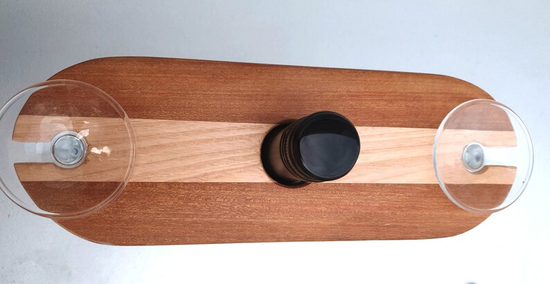 May include: A wooden serving tray with two glass holders and a center slot for a bottle. The tray is made of two types of wood, one light and one dark, and has a natural finish.