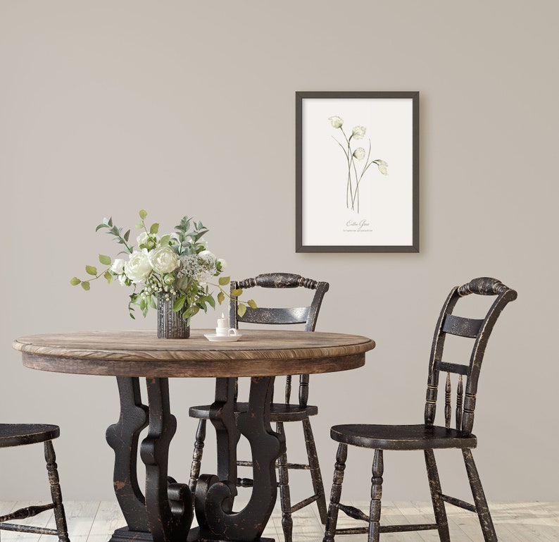 May include: A rustic wooden table with black painted legs and a black painted top. There are three black chairs around the table. A vase with white flowers sits on the table. A framed botanical print of white flowers hangs on the wall behind the table.