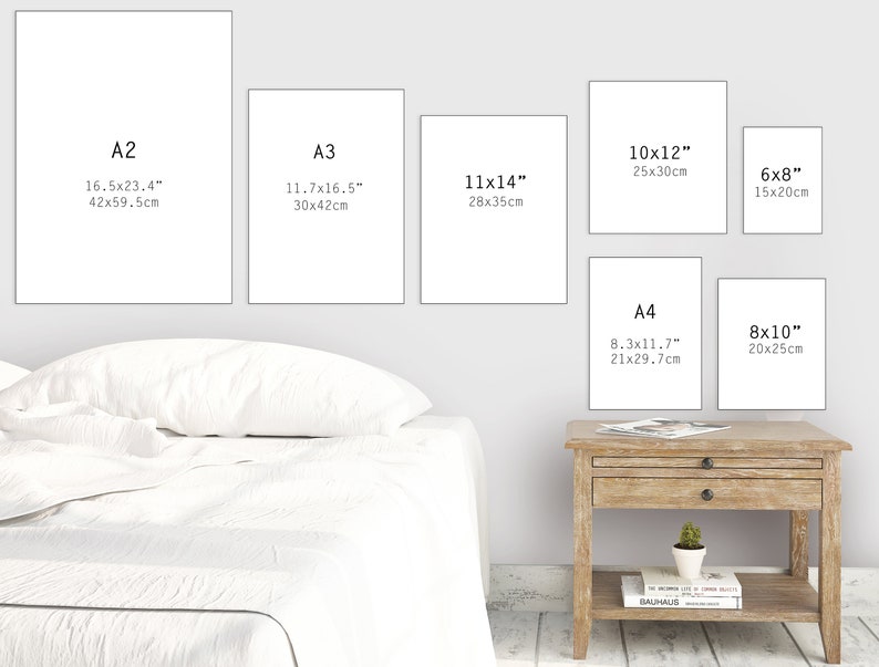 May include: A white wall with six different sized white frames, each with a black text label indicating the size of the frame in inches and centimeters. The frames are arranged in a staggered pattern, with the largest frame at the top left and the smallest frame at the bottom right. The frames are all empty, and the wall is a light gray color.