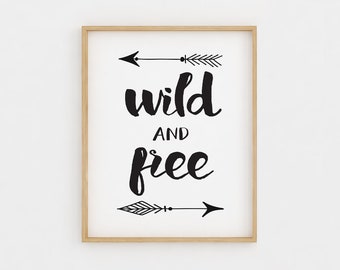 May include: Black and white printable wall art with the text "wild and free" and two arrows on either side of the text.